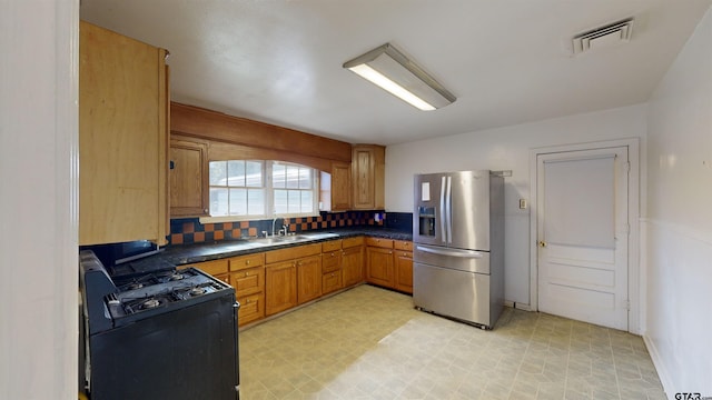 kitchen featuring stainless steel refrigerator with ice dispenser, dark countertops, visible vents, decorative backsplash, and gas stove