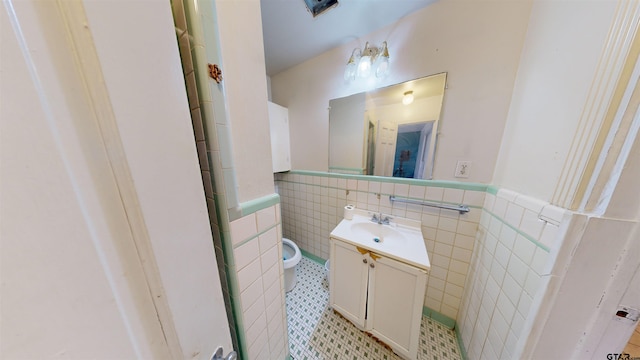 bathroom with toilet, a wainscoted wall, tile walls, and vanity