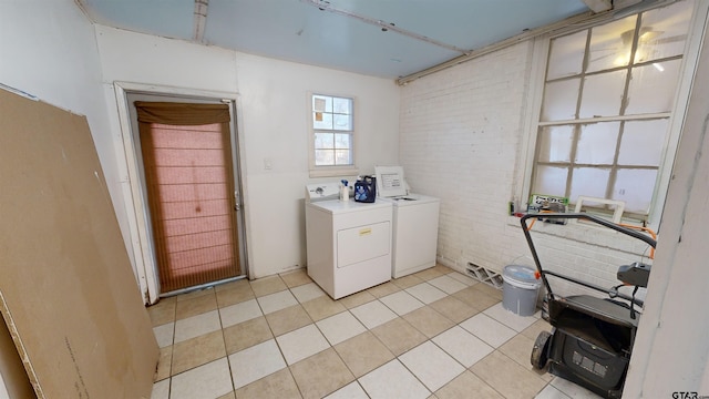 clothes washing area with independent washer and dryer, brick wall, and light tile patterned floors