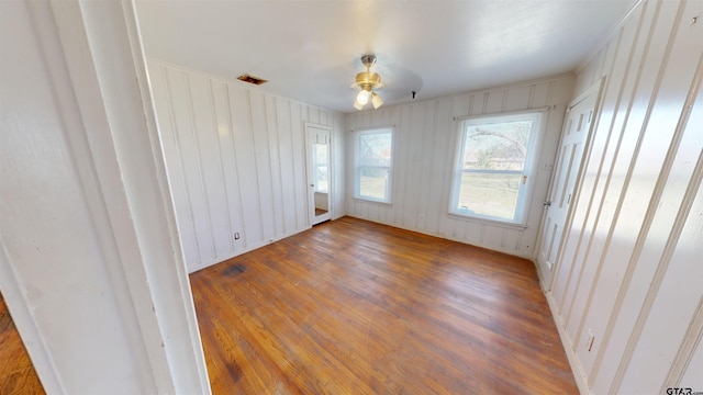 spare room with wood finished floors, visible vents, and a ceiling fan