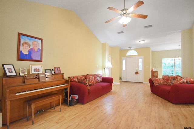 living room featuring wood finished floors, vaulted ceiling, a ceiling fan, a chandelier, and baseboards