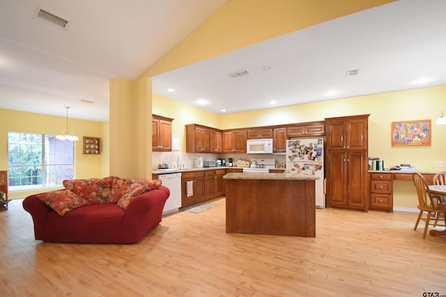 kitchen featuring white appliances, a chandelier, light wood-style floors, a kitchen island, and decorative backsplash