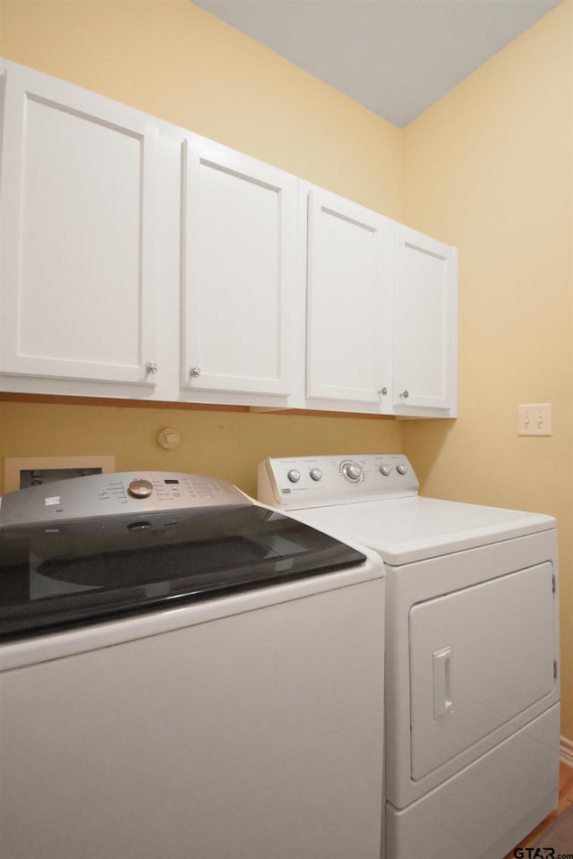 washroom featuring separate washer and dryer and cabinet space