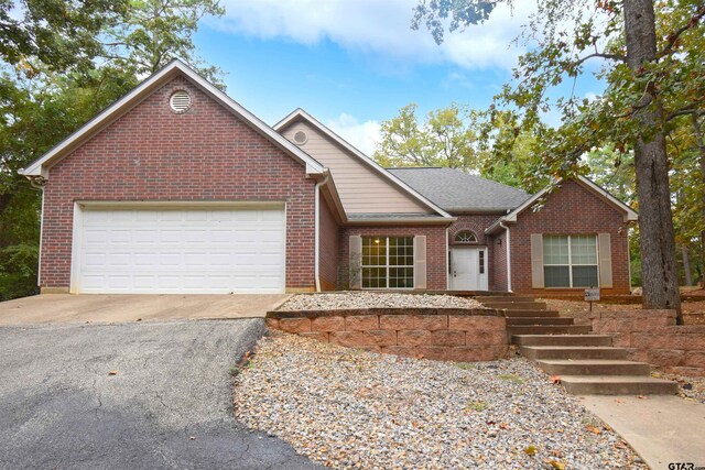 single story home featuring brick siding, driveway, and an attached garage