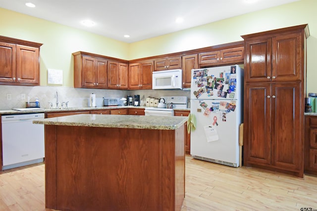 kitchen with white appliances, light wood-type flooring, tasteful backsplash, a kitchen island, and recessed lighting
