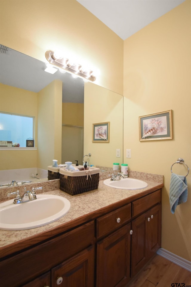 full bath with double vanity, wood finished floors, a shower with shower door, and a tub