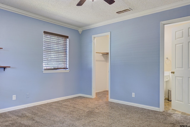 unfurnished bedroom with a walk in closet, a textured ceiling, light carpet, and ceiling fan