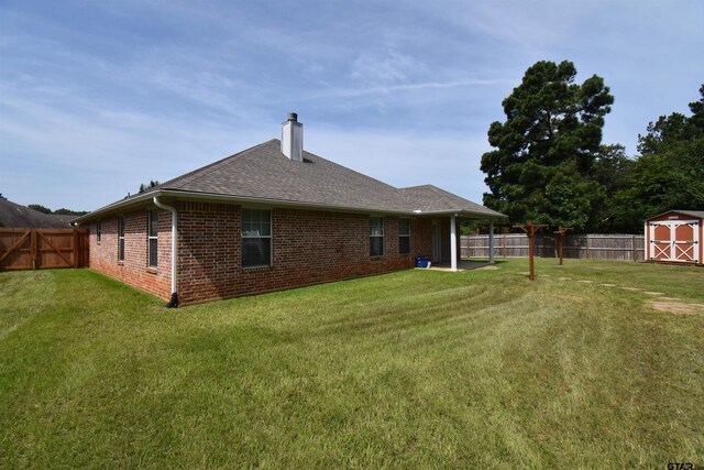 413 Maggie Cir, Flint, TX 75762 - back of property featuring a chimney, brick siding, a shed, a fenced backyard, and a shingled roof