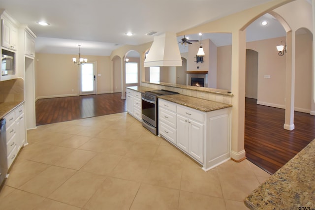 413 Maggie Cir, Flint, TX 75762 - kitchen featuring stainless steel electric stove, ceiling fan, a fireplace, custom range hood, and light wood finished floors