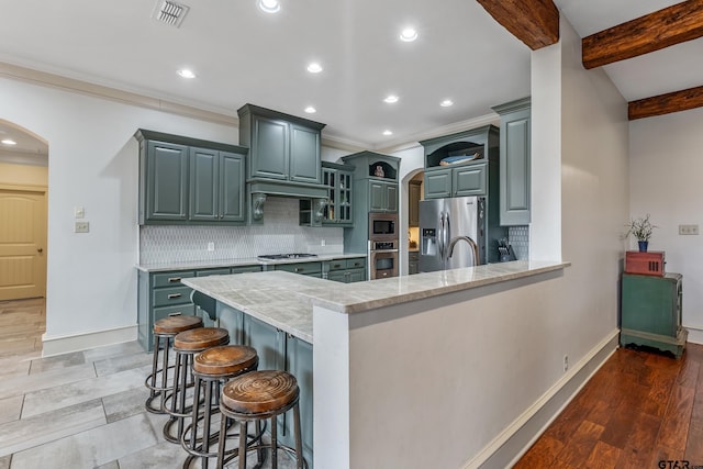 kitchen with beamed ceiling, a breakfast bar area, backsplash, kitchen peninsula, and stainless steel appliances