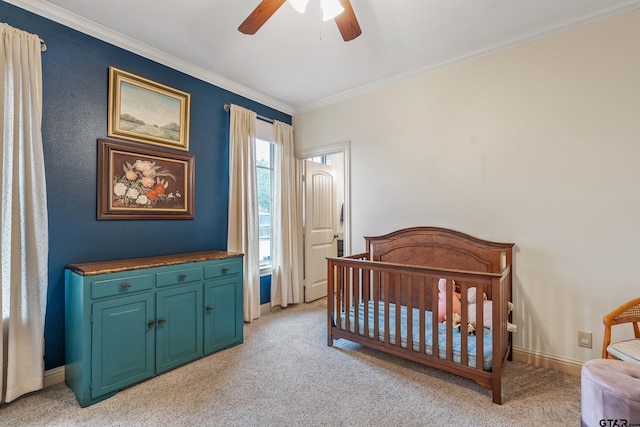 carpeted bedroom with crown molding, a nursery area, and ceiling fan