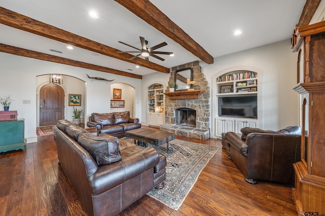 living room featuring dark hardwood / wood-style flooring, beam ceiling, a fireplace, and built in features