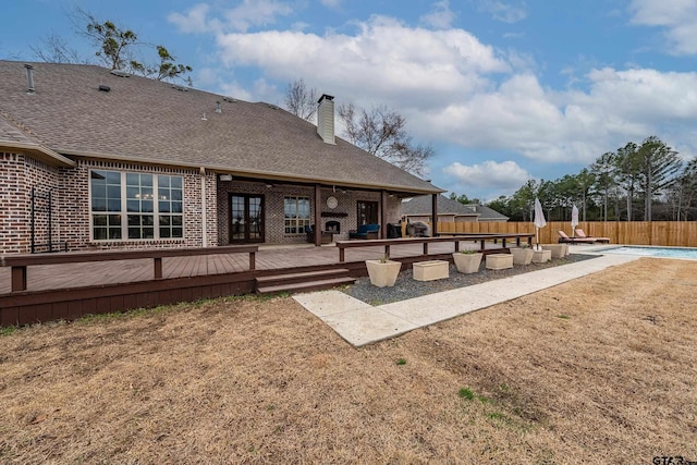 rear view of property featuring a pool side deck and a yard