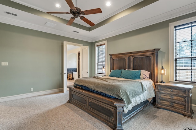 carpeted bedroom featuring multiple windows, a tray ceiling, ornamental molding, and ceiling fan