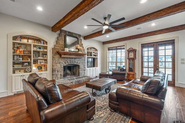 living room featuring built in features, hardwood / wood-style floors, beam ceiling, a fireplace, and french doors