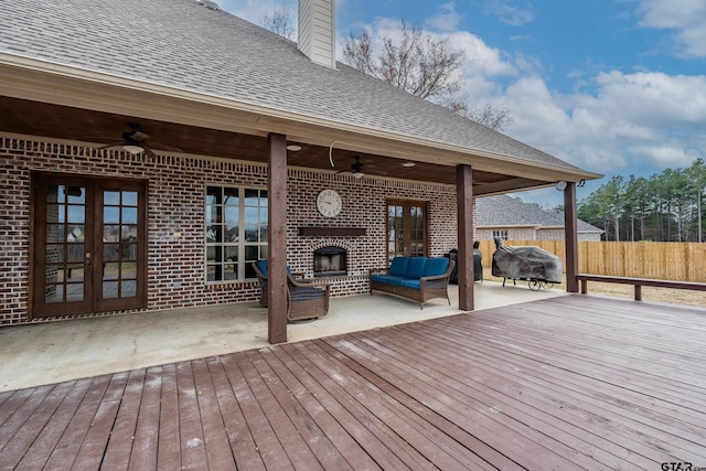 deck with an outdoor living space with a fireplace, a patio area, french doors, and ceiling fan