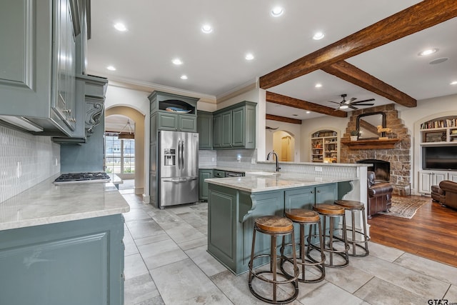 kitchen featuring a kitchen bar, sink, stainless steel fridge, kitchen peninsula, and a fireplace