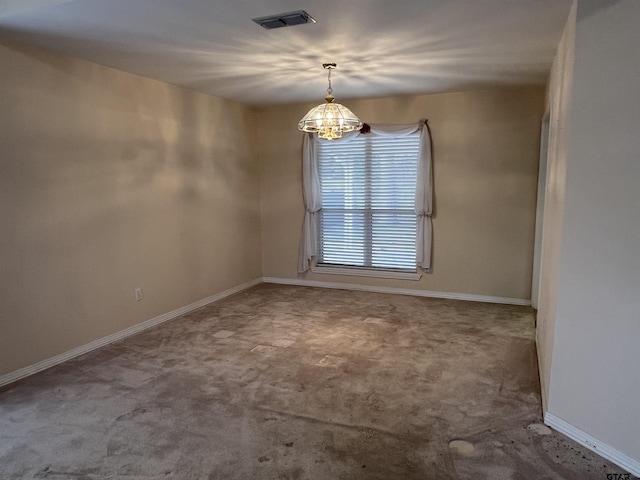 carpeted spare room featuring an inviting chandelier