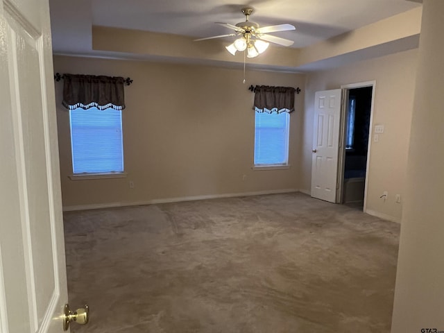 spare room featuring ceiling fan, carpet floors, and a tray ceiling