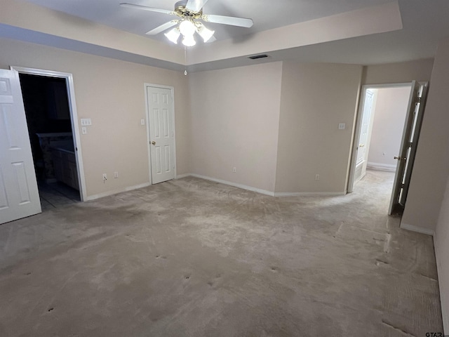 carpeted empty room featuring ceiling fan and a raised ceiling