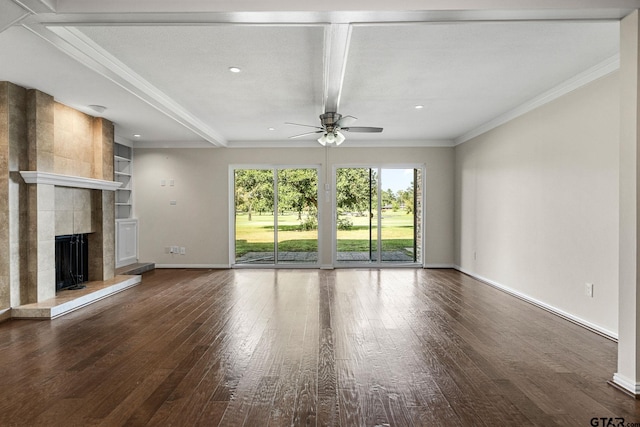 unfurnished living room with built in shelves, ornamental molding, dark wood-type flooring, a tile fireplace, and ceiling fan