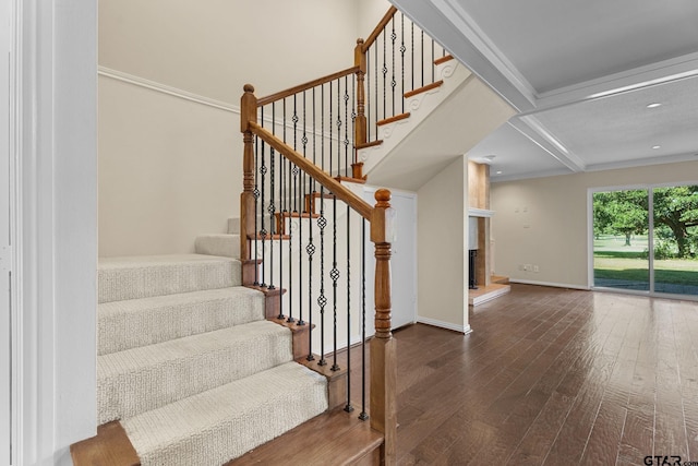 stairway with hardwood / wood-style flooring, beamed ceiling, a large fireplace, crown molding, and coffered ceiling