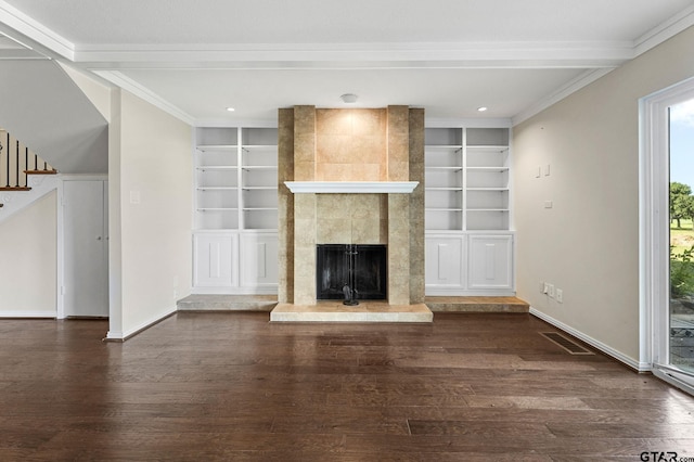 unfurnished living room featuring built in features, a tile fireplace, dark hardwood / wood-style flooring, and crown molding