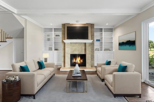 living room with a fireplace, wood-type flooring, built in features, and crown molding