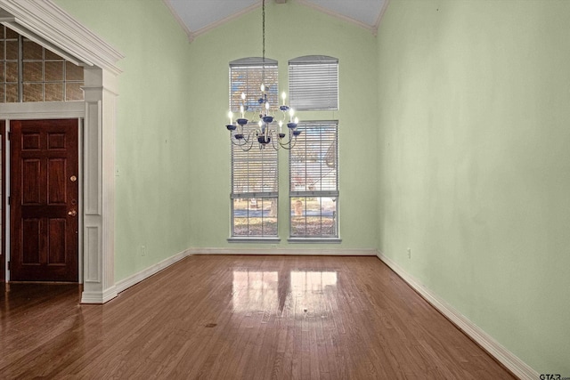 unfurnished dining area with crown molding, a chandelier, vaulted ceiling, and hardwood / wood-style flooring