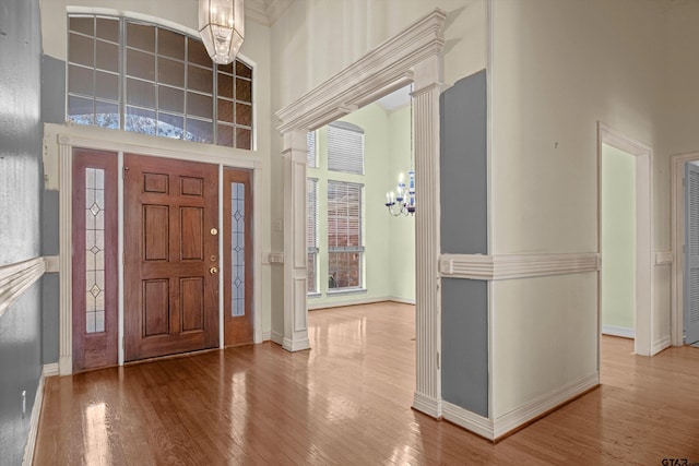 entryway with a towering ceiling, a chandelier, and hardwood / wood-style flooring