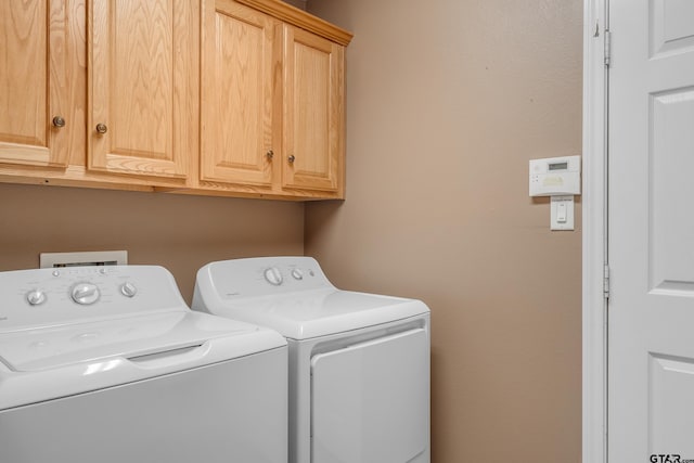 clothes washing area with cabinets and washing machine and dryer