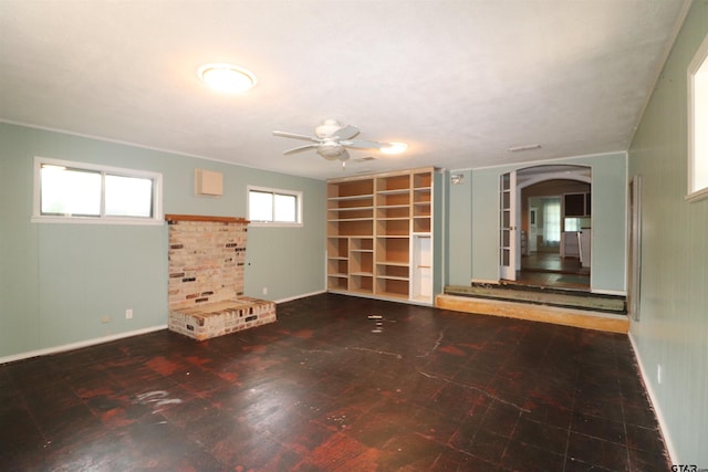 unfurnished room featuring built in shelves, ceiling fan, and a healthy amount of sunlight