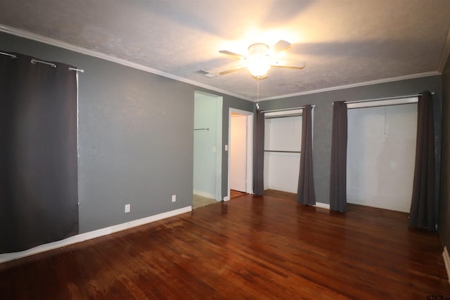 unfurnished bedroom with dark wood-type flooring, two closets, and ceiling fan