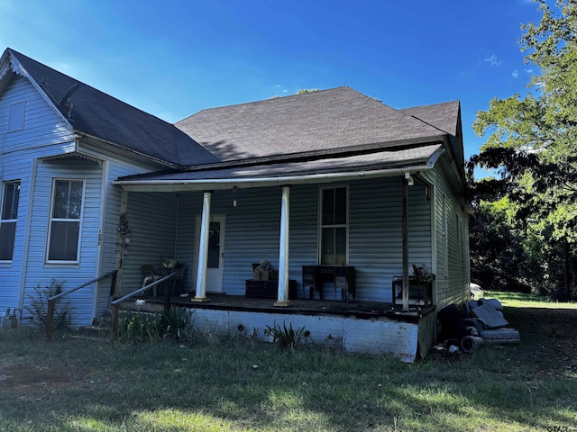 rear view of property featuring covered porch and a lawn