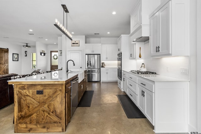 kitchen featuring pendant lighting, a kitchen island with sink, sink, white cabinetry, and stainless steel appliances