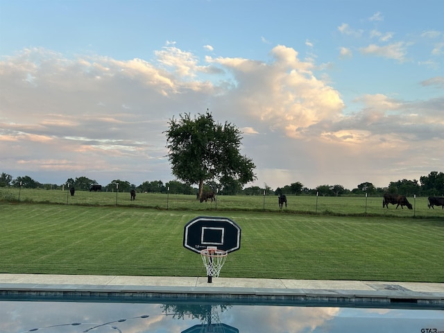 view of swimming pool featuring a rural view and a lawn