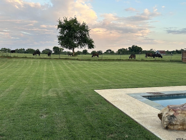 yard at dusk featuring a rural view