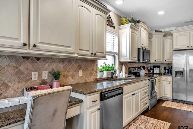 kitchen with dark stone counters, sink, dark hardwood / wood-style floors, ornamental molding, and stainless steel appliances