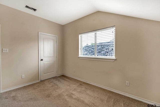 carpeted empty room featuring vaulted ceiling