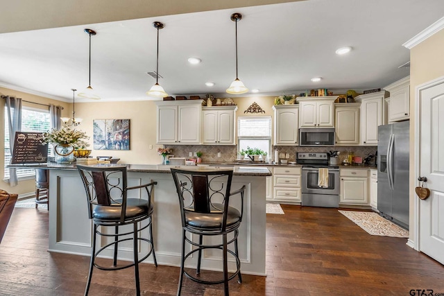 kitchen with appliances with stainless steel finishes, a breakfast bar, crown molding, pendant lighting, and dark hardwood / wood-style floors