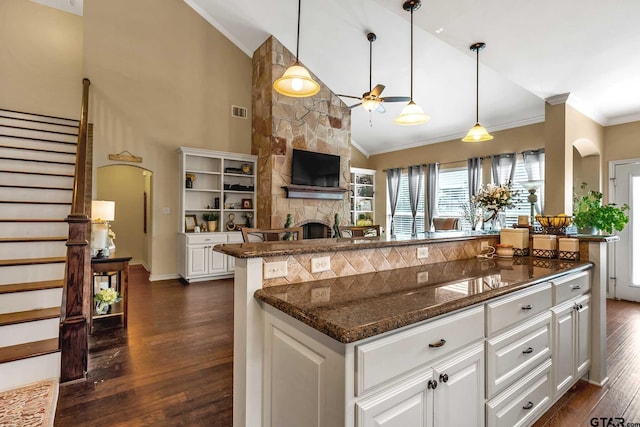 kitchen with white cabinets, a fireplace, high vaulted ceiling, and dark wood-type flooring