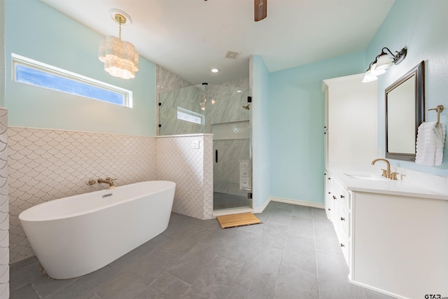 bathroom with tile patterned flooring, vanity, tile walls, and independent shower and bath