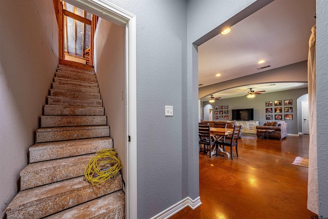 staircase featuring concrete floors and ceiling fan