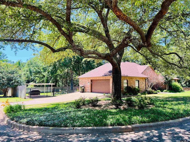 view of front facade featuring a front yard, fence, driveway, a garage, and brick siding