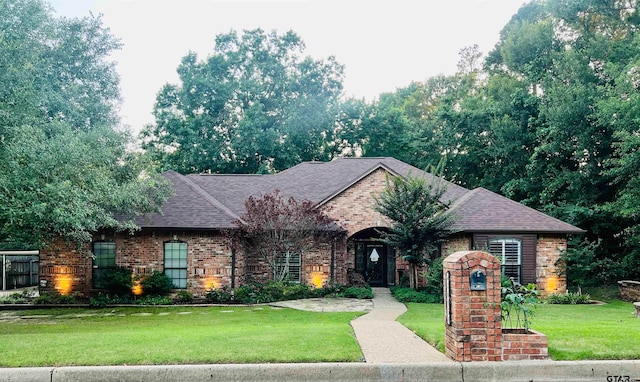 single story home featuring a front yard, brick siding, and a shingled roof