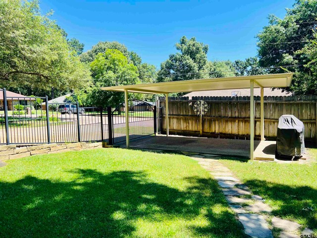 view of yard featuring a carport, a gate, and fence