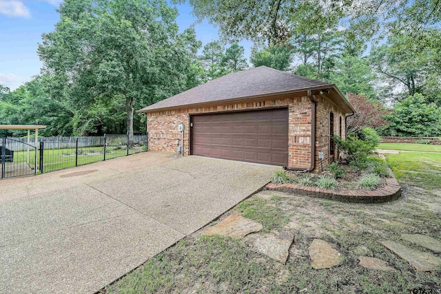 garage with concrete driveway and fence