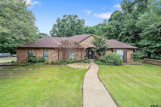 ranch-style house with brick siding, a front lawn, and roof with shingles