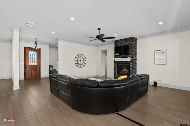 living room featuring ornate columns, a fireplace, wood-type flooring, ceiling fan, and crown molding