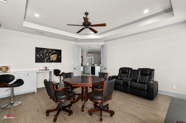 dining space with a raised ceiling, crown molding, and light hardwood / wood-style flooring